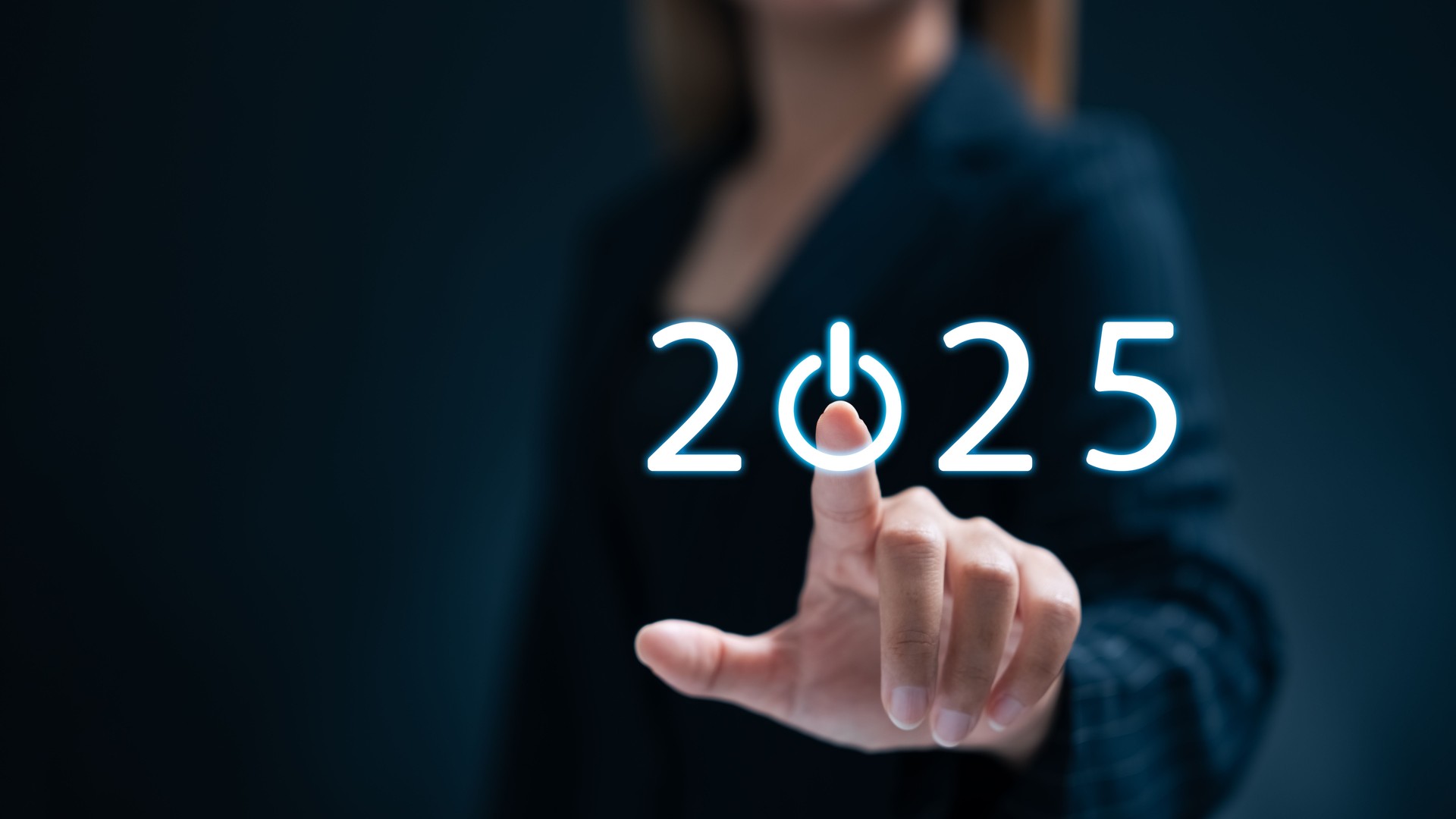 Una empresaria toca un botón de inicio para el Año Nuevo 2025 para establecer metas y desarrollar estrategias.